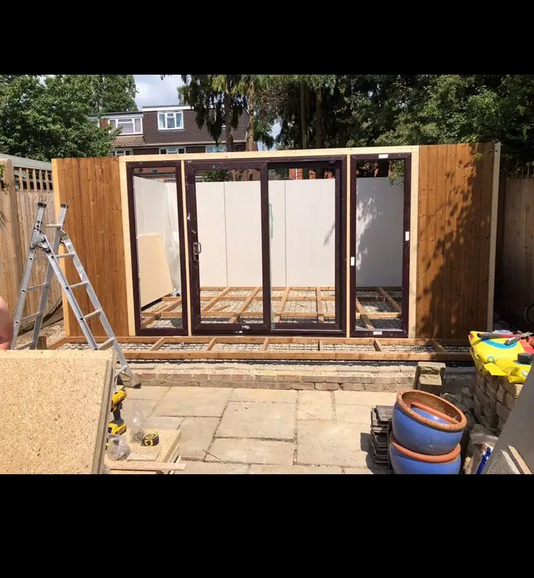The same garden mid-build — timber frame, exposed joists and a ladder before completion